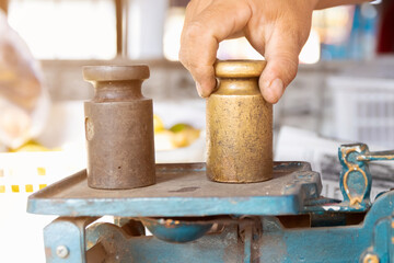 Hand putting weight on iron scale weights.