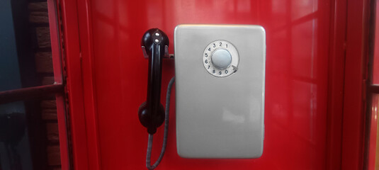 grey old Soviet payphone. telephone hanging inside red booth.