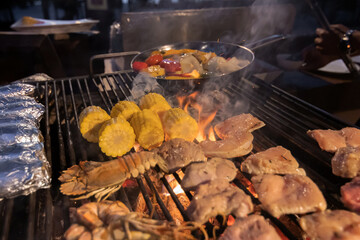Chef cooking seafood and meat on a charcoal grill at barbeque night.