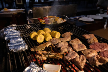 Chef cooking seafood and meat on a charcoal grill at barbeque night.