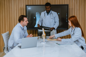 Surgeon and radiologist discuss Pt's ankle's MRI for treatment plan. Multicultural boardroom meeting