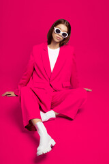 Fashion asian female model in pink suit, white boots and sunglasses.