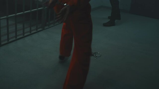 Prisoner in orange uniform fights with jailer. Another criminal strangles prison employee and removes handcuffs from cellmate. Escape from jail. Fighting in detention center or correctional facility.
