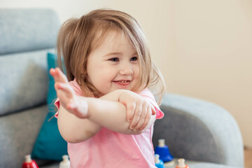 Close-up portrait of a little Asian girl, stretched her arms forward, looking away, smiling. Copy space