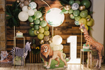 Arch decorated green, brown, golden balloons, neon numbers one, paper leaves. Birthday cake for 1...