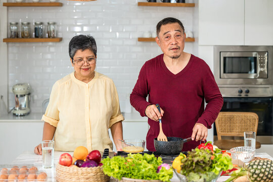 Couple Senior Asian Elder Happy Living In Home Kitchen. Elderly Couple Cooking In A Kitchen. Happy Mature Couple Family Together In The Kitchen,  Active Seniors. Older People Relationship And Activity