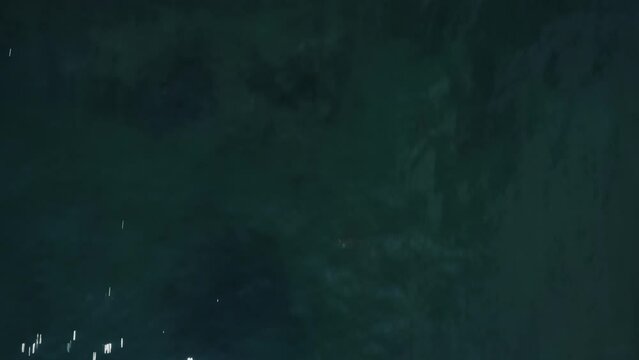 ドローン撮影：夏の青空に照らされた海を後進しながらティルトアップ撮影