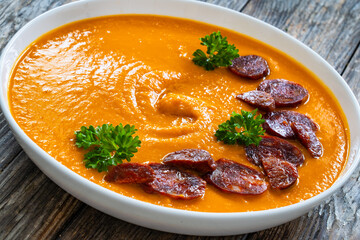 Sweet potatoes cream soup with choriso sausage on wooden background