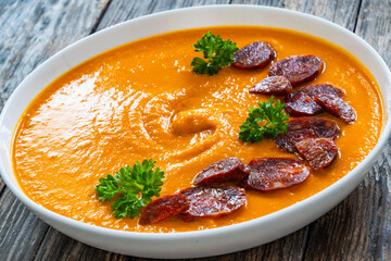 Sweet potatoes cream soup with choriso sausage on wooden background