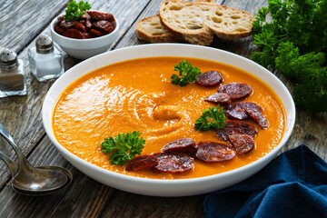 Sweet potatoes cream soup with choriso sausage on wooden background
