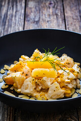 Fruit salad - peaches, pineapples, almonds and corn in mayonnaise on wooden table
