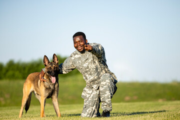 Portrait of smiling soldier and military dog looking to the camera.
