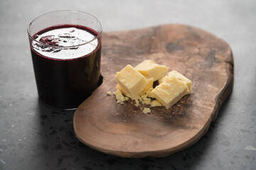 White cheddar cheese pieces on olive wood board with berry juice