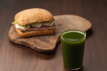 Green matcha drink in tumbler glass with sandwich on background