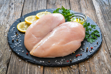 Fresh raw chicken breasts on cutting board with spices on wooden background
