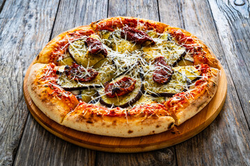 Pizza with eggplant, sun dried tomatoes and parmesan cheese on wooden table
