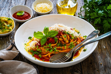 Linguine with tomato sauce, parmesan cheese and basil leaves served on wooden table 