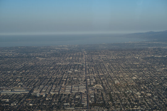 Aerial view of Los Angeles, looking across a massive urban sprawl towards the coast including Long Beach, Santa Monica, and Venice Beach. The Pacific Ocean goes off into the distance.