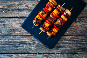 Meat skewers - grilled pork loin, bell pepper and pineapple on wooden background

