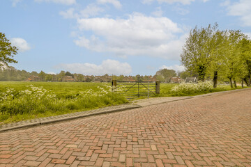 a brick path with flowers and trees in the background on a sunny day, as seen from an angle point of view