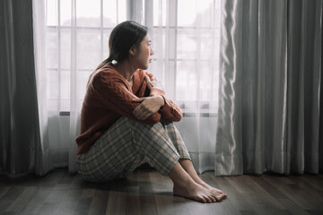 Sad and depressed young female sitting on the floor in the room, sad mood,feel tired, lonely and...