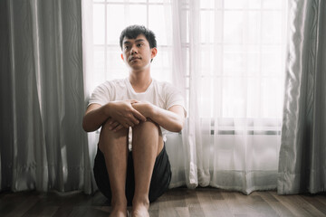 Fototapeta na wymiar Sad and depressed young male sitting on the floor in the room, sad mood,feel tired, lonely and unhappy concept.