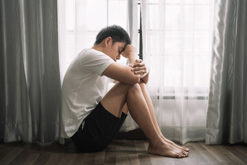 Sad and depressed young male sitting on the floor in the room, sad mood,feel tired, lonely and unhappy concept.