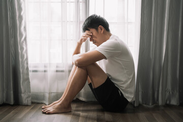 Sad and depressed young male sitting on the floor in the room, sad mood,feel tired, lonely and unhappy concept.