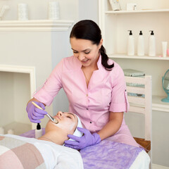 Cosmetologist doing facial peeling procedure in beauty spa salon
