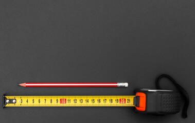 Industrial measuring tape with pencil on black. Copy space. - 626500555
