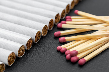Matches with cigarettes on black background. Close up.