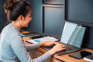 Asian woman working from home using computer and drinking coffee in her bedroom document finance and conference online meeting for new projects