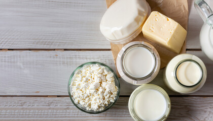 Dairy products in glass jars on light background. Top view, wooden table