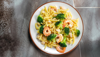 Pasta with broccoli and shrimp on a plate, top view