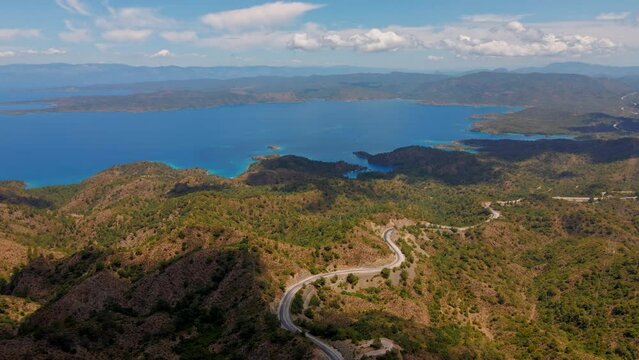 aerial drone footage of beautiful scenic landscape of Marmaris peninsula, mountains and hills with green woods and curved road to Datca destination. peninsula surrounded Aegian and Mediterranean seas.