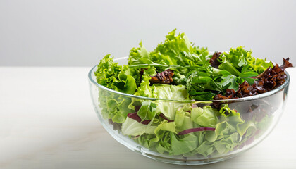 Mix of green salad in glass bowl on the table. Simple food for diet or healthy eating. Side view,...