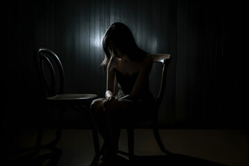 The depression woman sit on the chair on dark background, sad asian woman silhouette in dark, dark light photography