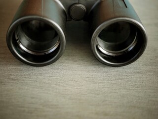Black binoculars on a wooden table closeup