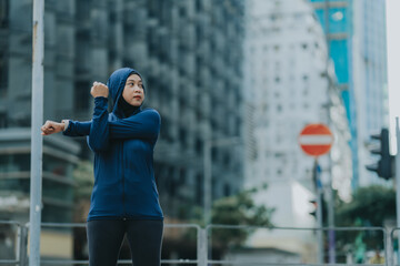 Glad smiling young asian muslim female in hijab with fitness tracker running on building background outdoor. Fitness outside, jogging in morning, body and health care, training, concept muslim sport.