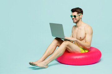Full body young sexy IT man wear green shorts swimsuit relax near hotel pool sit on rubber ring...