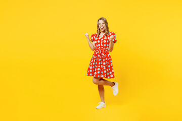 Full body young smiling woman wear red dress casual clothes doing winner gesture celebrate...