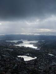 Norwegian landscape of a town with lakes and sunlight beaming through the dark clouds