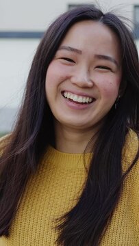 Portrait of young student asian woman smiling at camera sitting at college campus. Education, chinese people and positive emotion concept. Vertical aspect screen video.