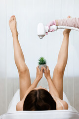 Bikini Laser hair removal. Woman lifted her beautiful long legs apart, holding a prickly plant...