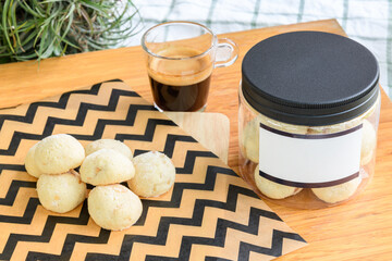 Cookies in plastic box next to black coffee on a wooden table in backyard