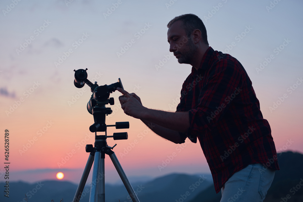 Wall mural astronomer looking at the sun with a telescope and using a cellphone.