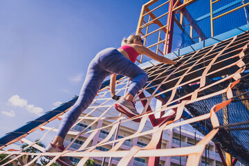 Athletic young woman working out and climbing at the training camp.