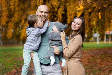 Fototapeta premium Dad holds his son and daughter in his arms, happy wife, a walk with his family