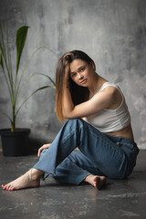 Portrait of a young attractive girl in a white T-shirt and jeans. A girl of oriental appearance in the interior of a stylish apartment. Lifestyle