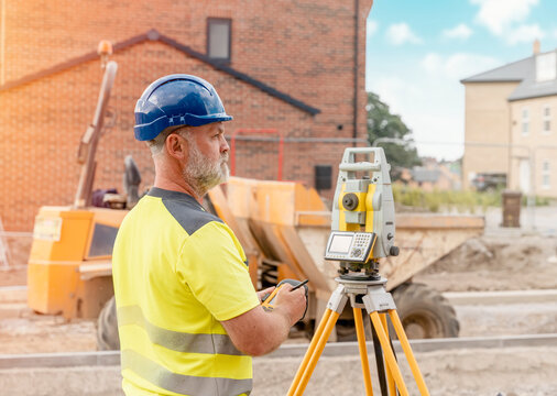 A Man Site Engineer Surveyor Working With Theodolite Total Station EDM Equipment On A Building Construction Site Outdoors